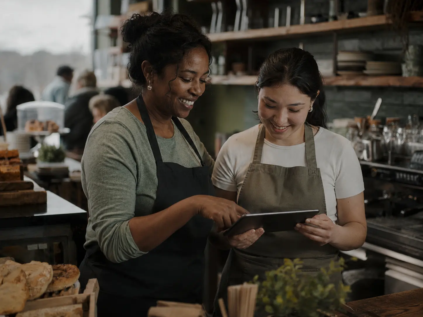 Two Irish business owners working together over a tablet in their café