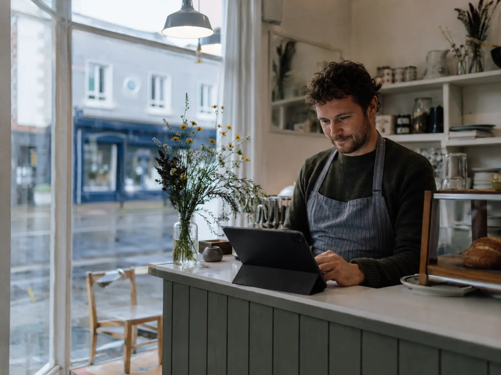 Irish café owner updating their own website on a tablet behind the counter