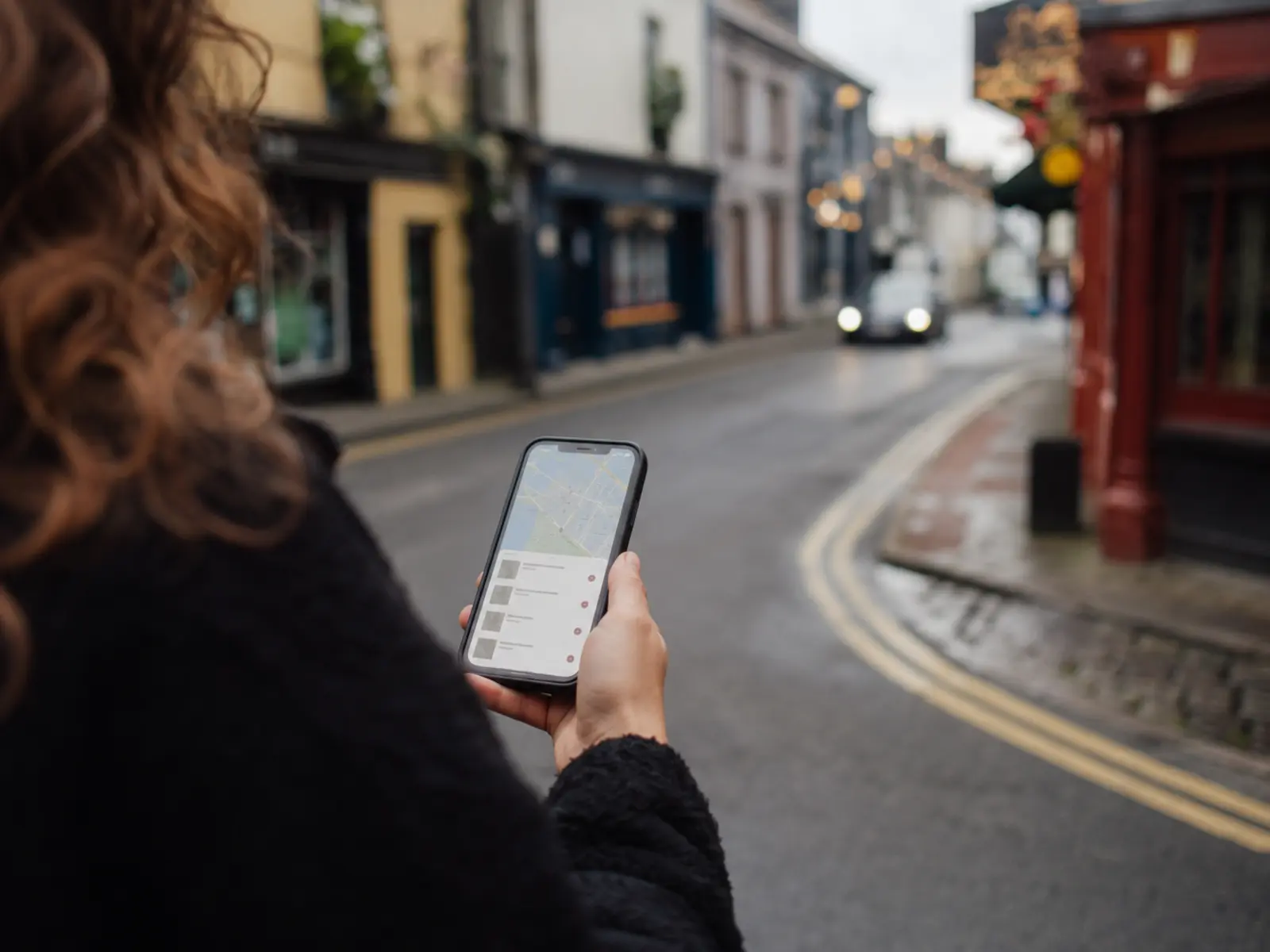 Hand holding a phone showing local map results on an Irish street